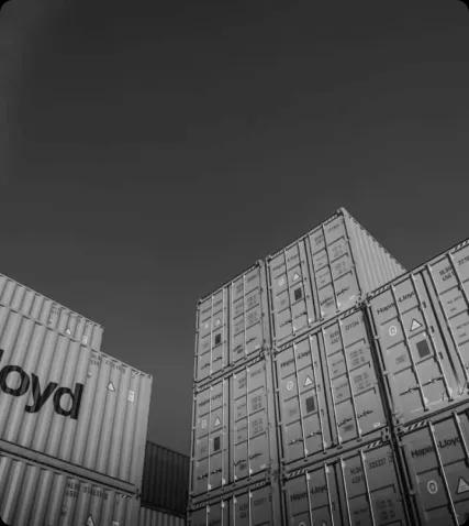 Символ организации и точности в логистике Монохромное изображение стопки контейнеров, аккуратно уложенных друг на друга, на фоне чистого неба, символизирующее эффективную логистику и организацию.